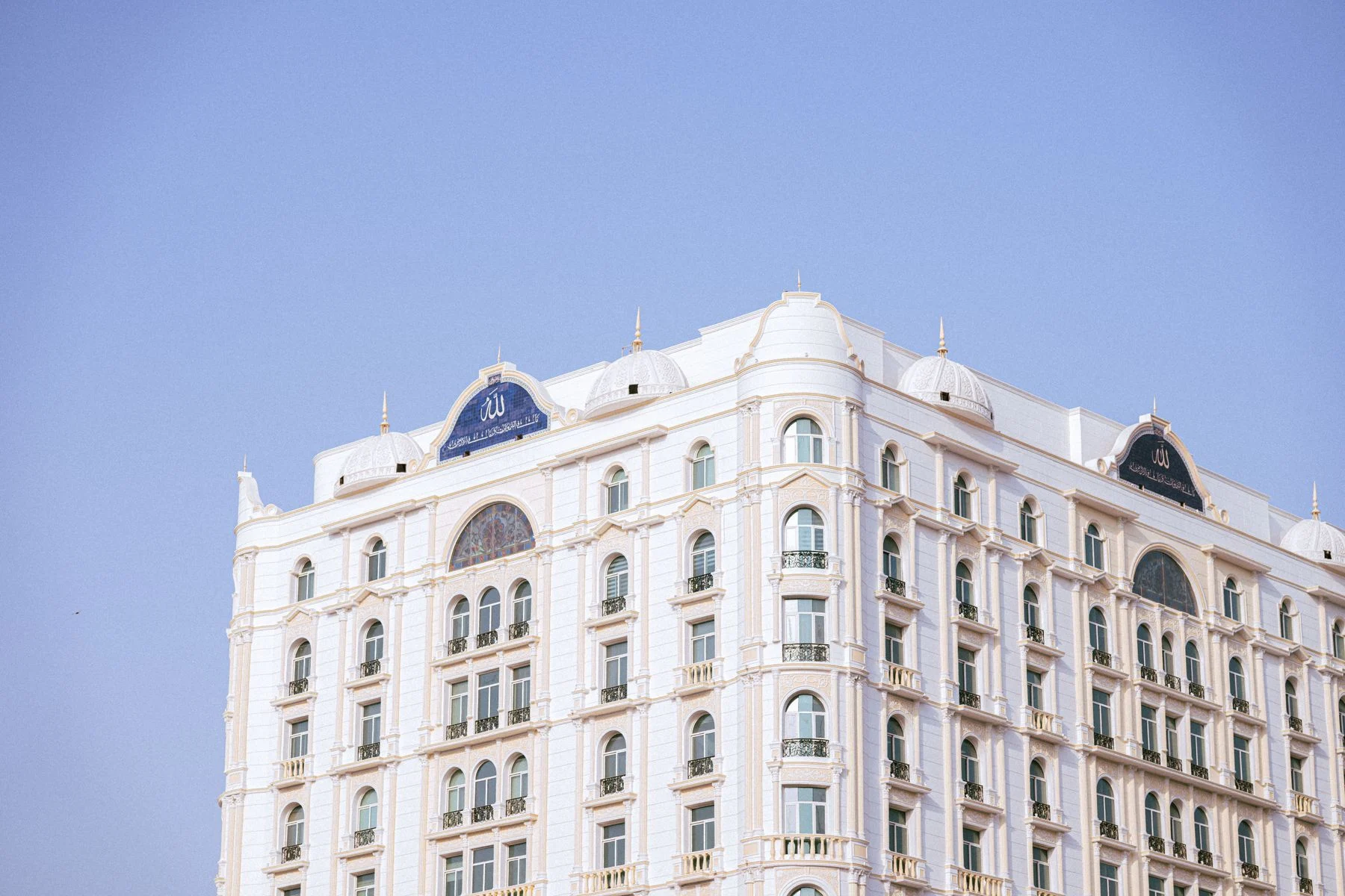 A white hotel facade photographed beneath a clear blue sky.